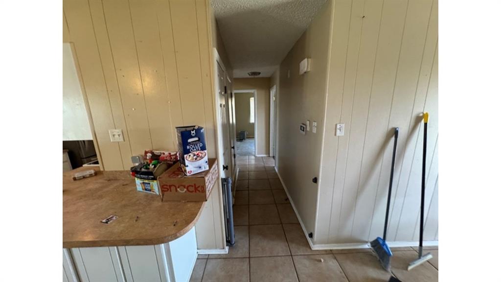 4004 Vicky Street Big Spring, TX 79720 - Photo 8 of 37 Hall featuring wooden walls, light tile patterned flooring, and a textured ceiling