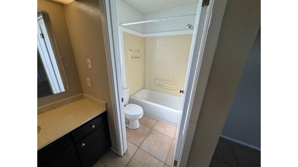 4004 Vicky Street Big Spring, TX 79720 - Photo 10 of 37 Full bathroom with vanity, washtub / shower combination, light tile patterned floors, and a textured ceiling
