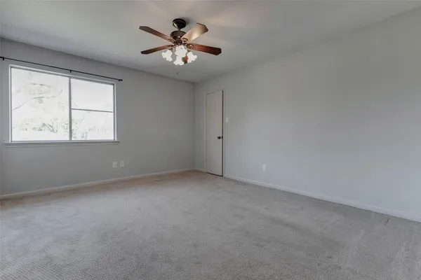 an empty room with a chandelier fan and windows