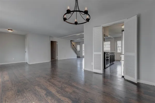 a hallway with wooden floor furniture and a chandelier