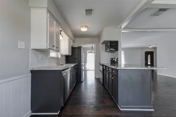 a kitchen with stainless steel appliances granite countertop lots of counter top space and wooden floor