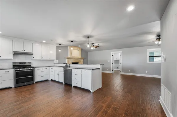 a large kitchen with hardwood floor a sink stainless steel appliances and cabinets