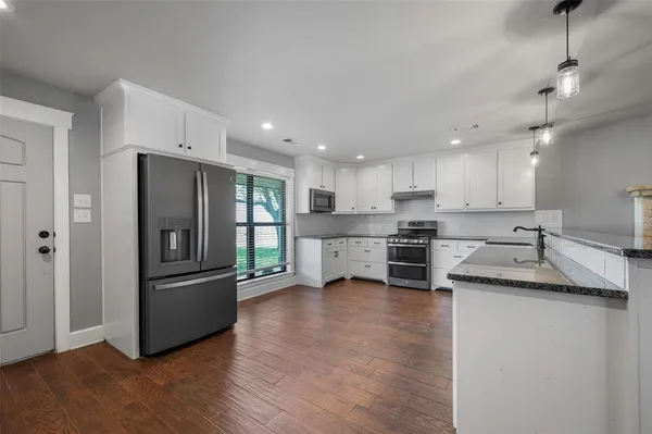a kitchen with stainless steel appliances granite countertop a refrigerator a sink a stove and oven with wooden floor