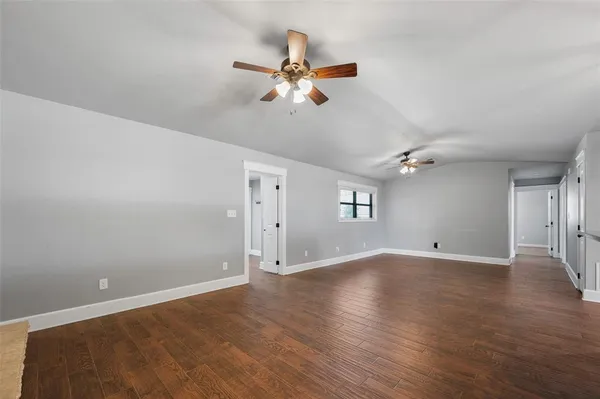 an empty room with wooden floor ceiling fan and windows