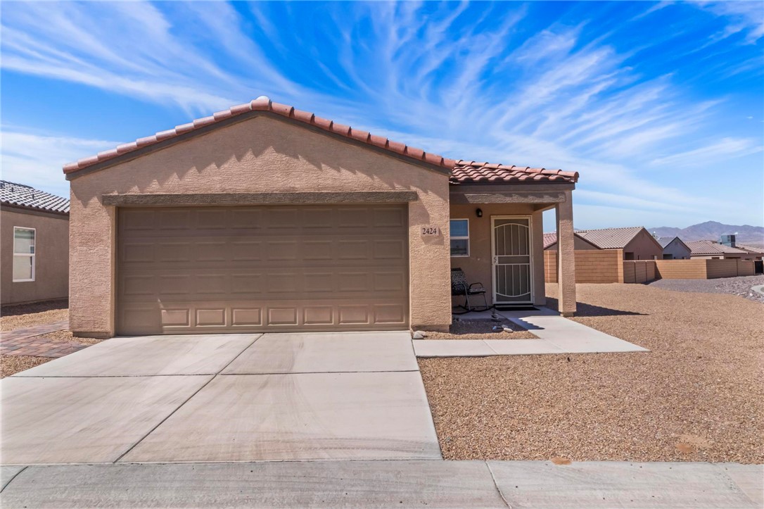 2424 Granite Road Bullhead City, AZ 86442 - Photo 49 of 50 Stucco exterior featuring a two-car garage, covered entry, and tile roof accents
