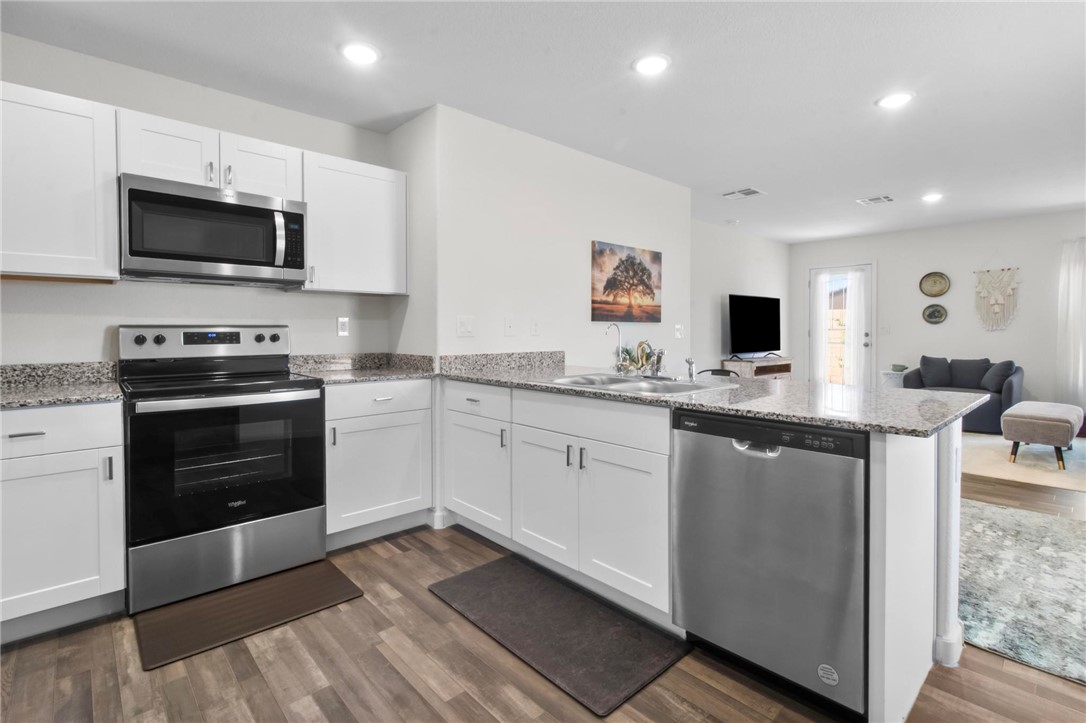 2424 Granite Road Bullhead City, AZ 86442 - Photo 9 of 50 Modern kitchen featuring white cabinetry, stainless steel appliances, speckled countertops, and wood-finish flooring