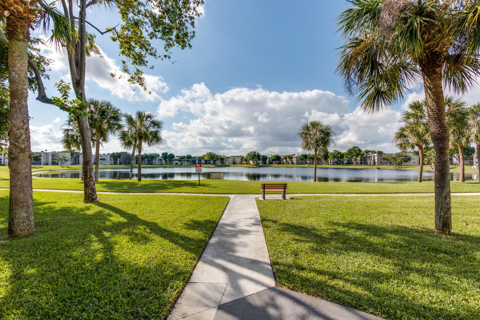 5220 Las Verdes Circle, Unit 211 Delray Beach, FL 33484 - Photo 21 of 57 a view of an swimming pool with a big yard and palm trees