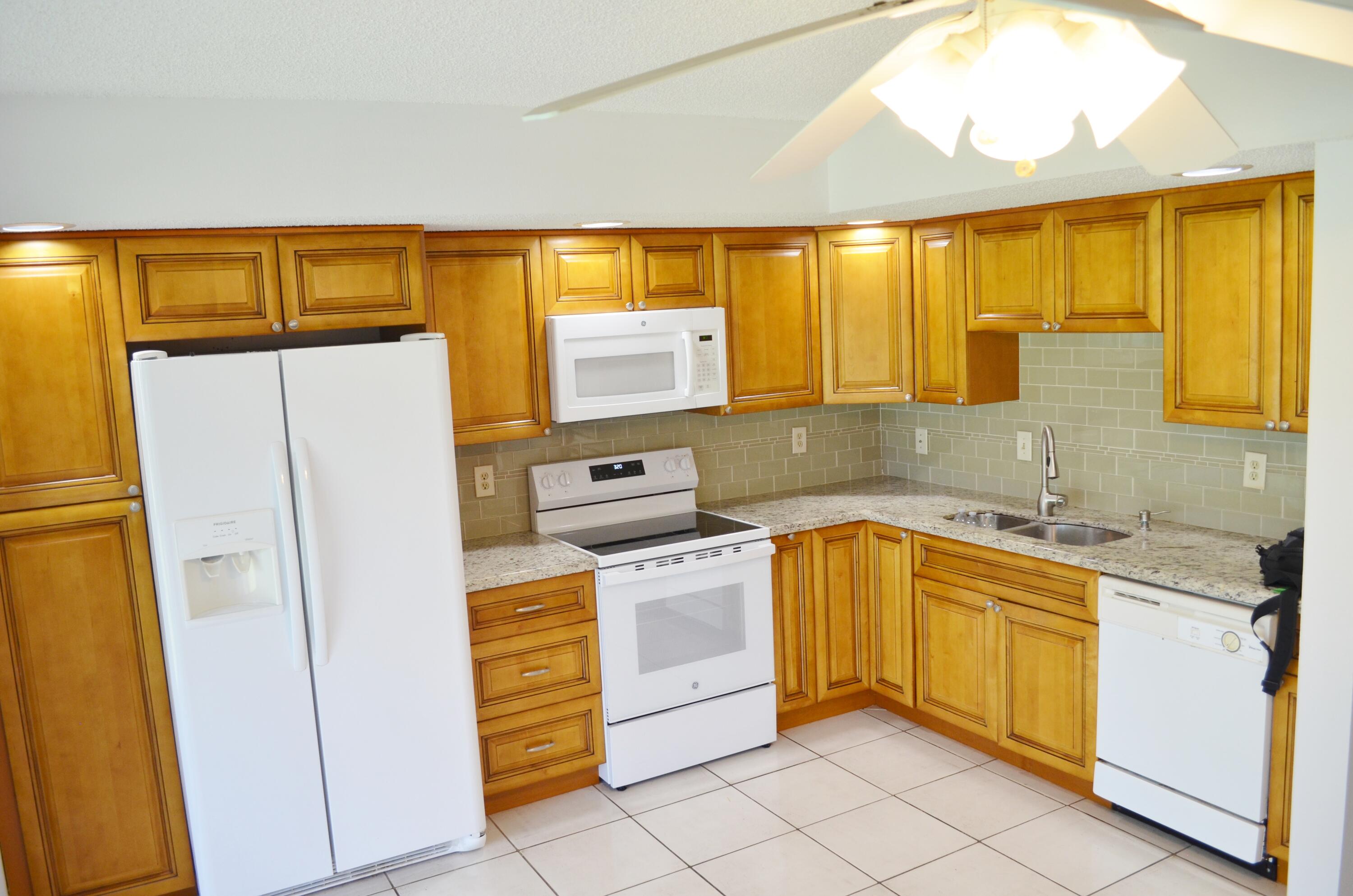 5220 Las Verdes Circle, Unit 211 Delray Beach, FL 33484 - Photo 4 of 57 a kitchen with a refrigerator and a sink