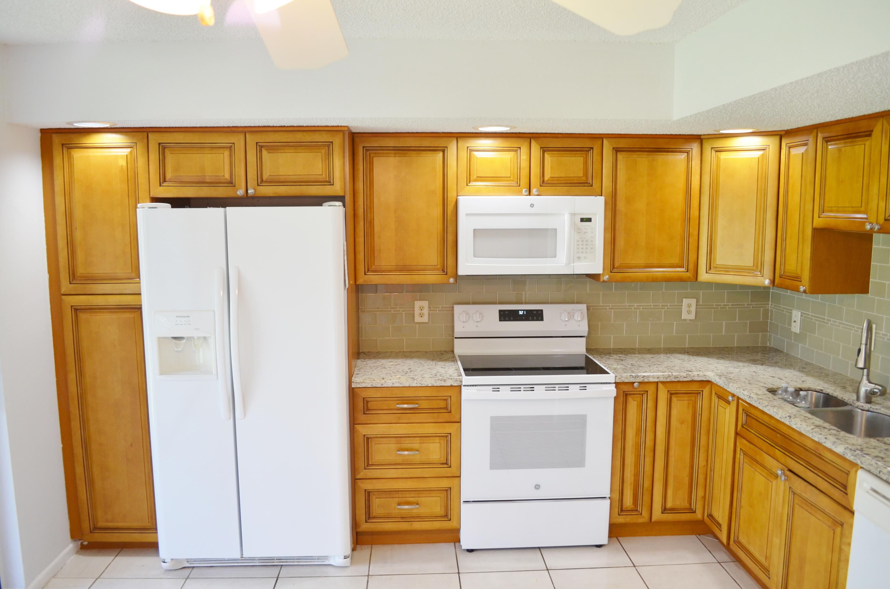 5220 Las Verdes Circle, Unit 211 Delray Beach, FL 33484 - Photo 5 of 57 a kitchen with a stove top oven cabinets and a refrigerator