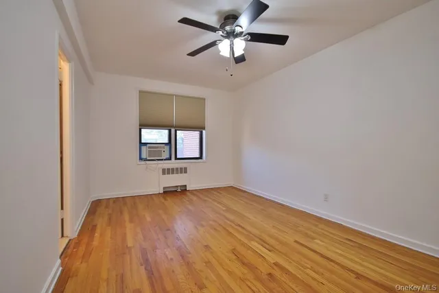 a view of a big room with wooden floor and windows