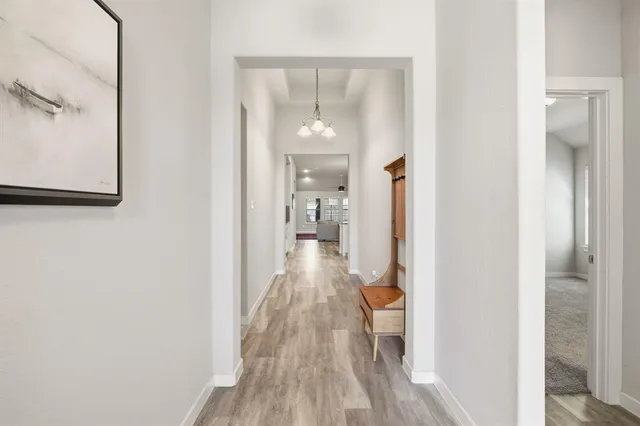 a view of a hallway with wooden floor and a bathroom