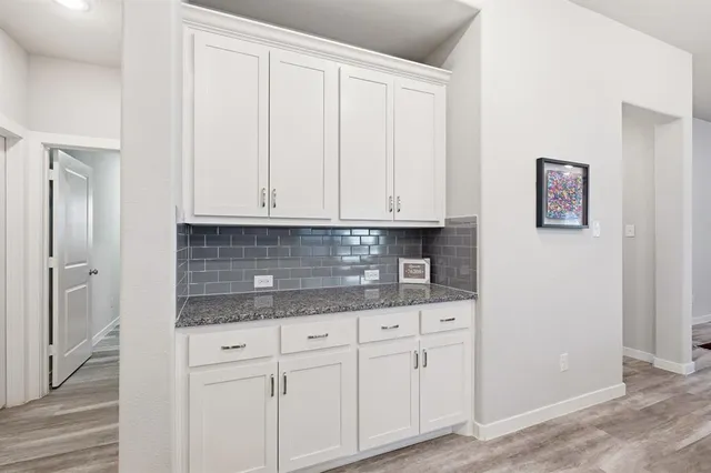 a kitchen with granite countertop white cabinets and stainless steel appliances