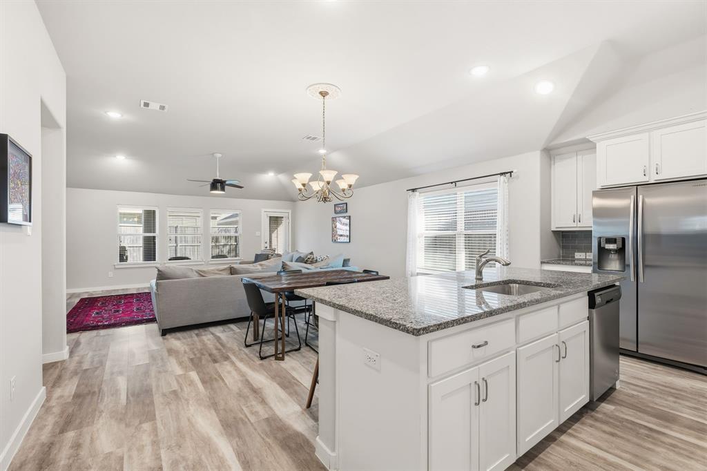 3921 Madison Lane Denton, TX 76208 - Photo 4 of 37 a kitchen with stainless steel appliances granite countertop a sink dishwasher and white cabinets with wooden floor