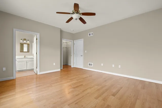 a view of empty room with wooden floor and ceiling fan
