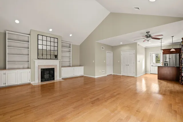 a view of a livingroom with a fireplace a ceiling fan and windows