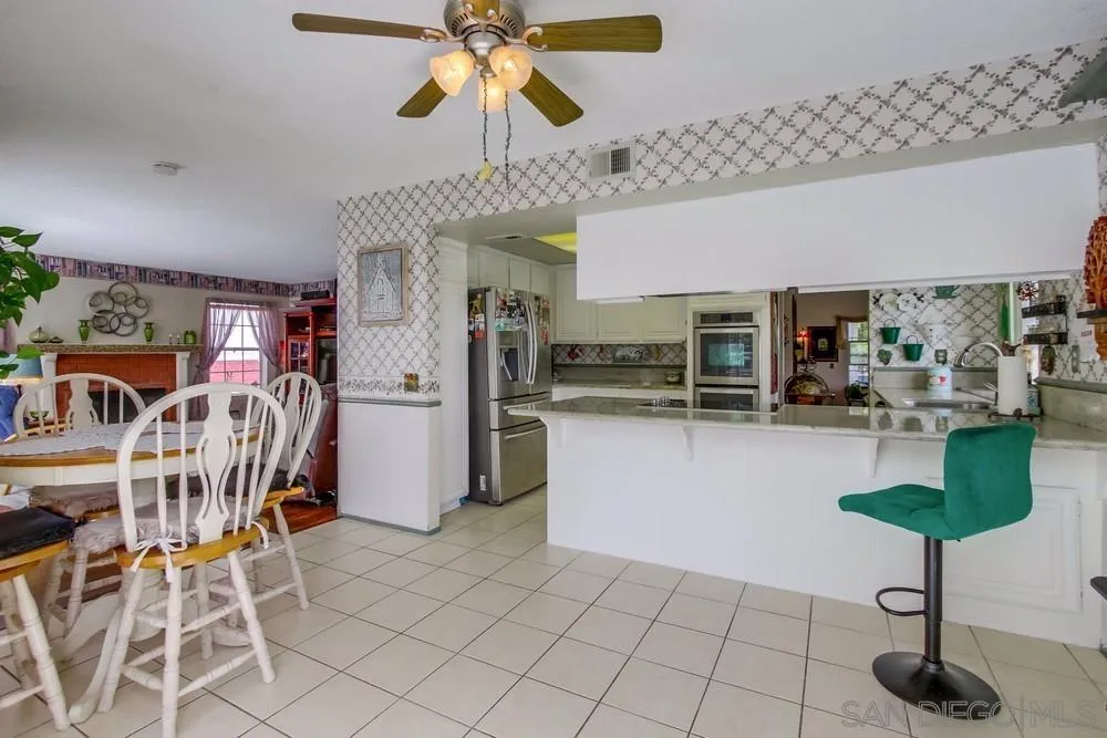 13590 Freeport Road San Diego, CA 92129 - Photo 24 of 58 a kitchen with stainless steel appliances kitchen island granite countertop a table and chairs in it