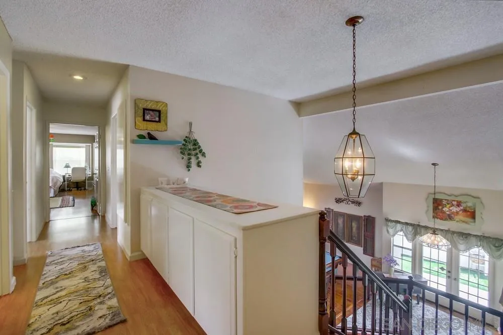 13590 Freeport Road San Diego, CA 92129 - Photo 41 of 58 a view of a hallway to a livingroom with wooden floor and furniture