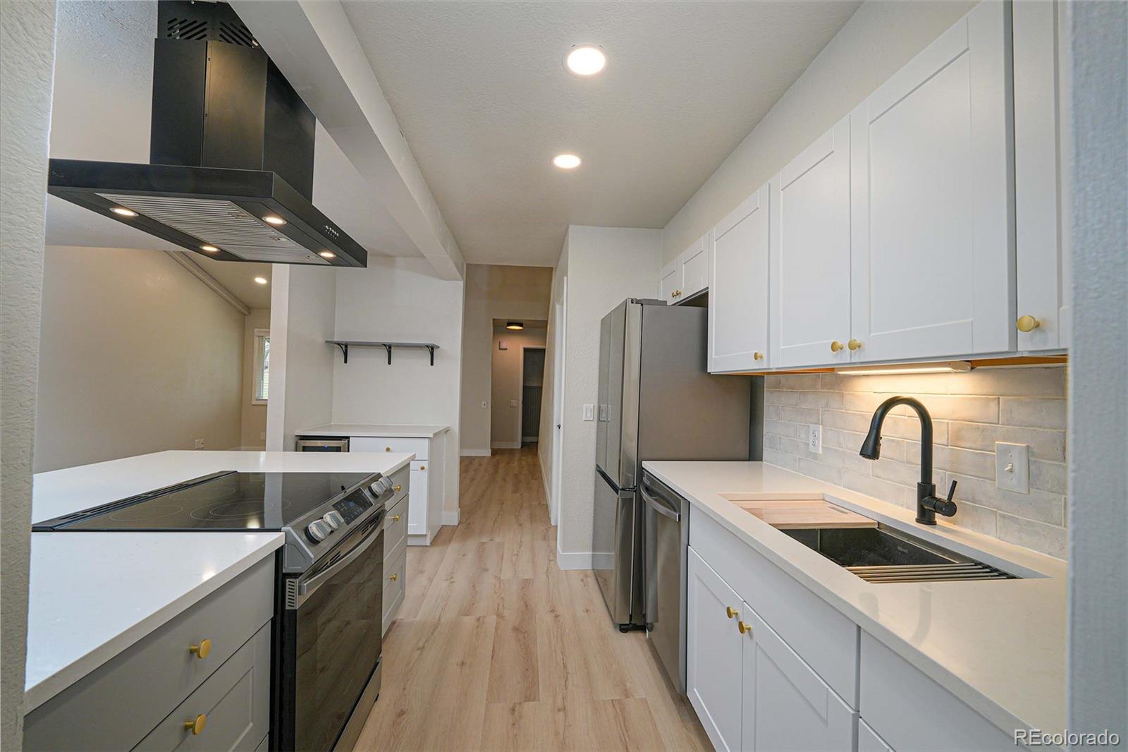 a kitchen with stainless steel appliances a sink dishwasher and a stove with wooden floor