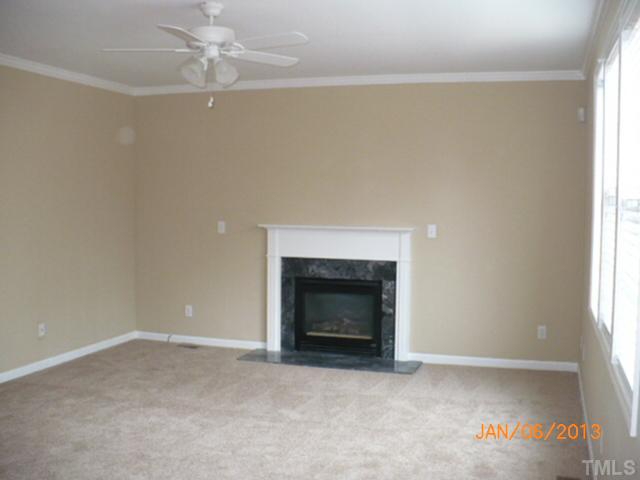 2512 Spruce Shadows Lane Raleigh, NC 27614 - Photo 7 of 22 an empty room with a fireplace and fan