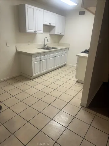 a kitchen with a sink a stove top oven and white cabinets
