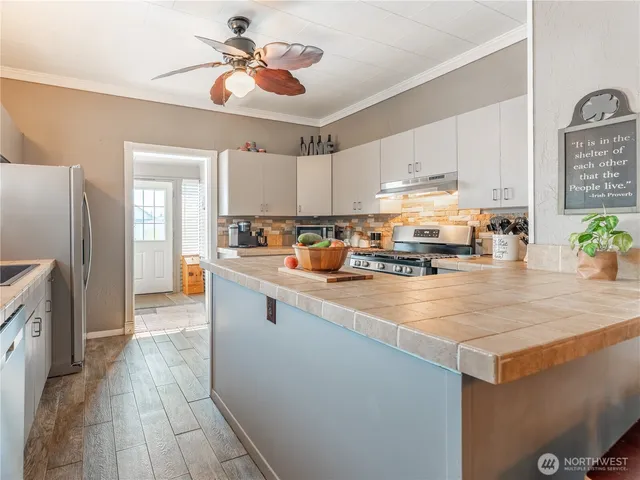 a kitchen with stainless steel appliances kitchen island granite countertop a sink a stove top oven a counter space and cabinets