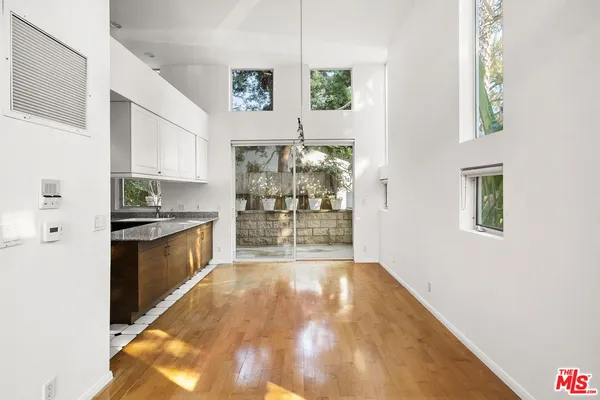 a large white kitchen with kitchen island granite countertop a refrigerator a stove a sink and a window