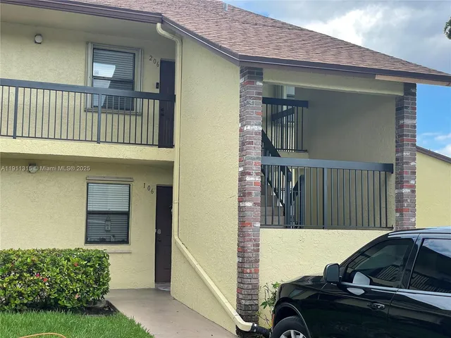 a view of a house with brick walls and a yard with plants