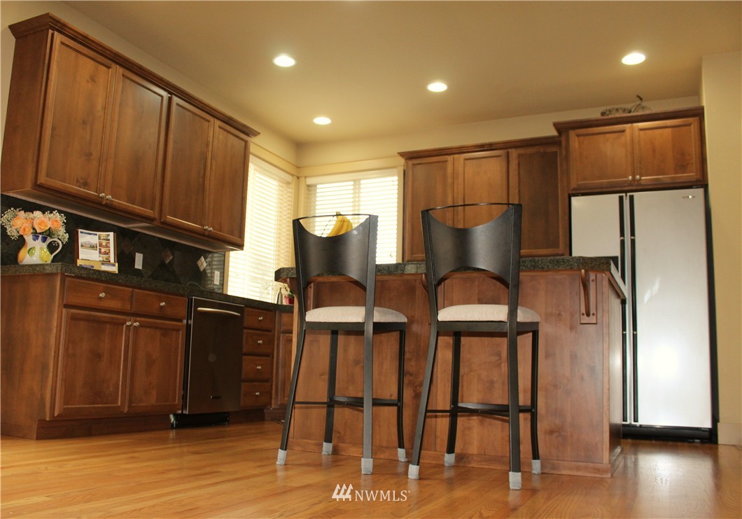 3808 186th Street Southeast Bothell, WA 98012 - Photo 7 of 25 a kitchen with stainless steel appliances granite countertop a refrigerator a stove and a microwave with wooden floor