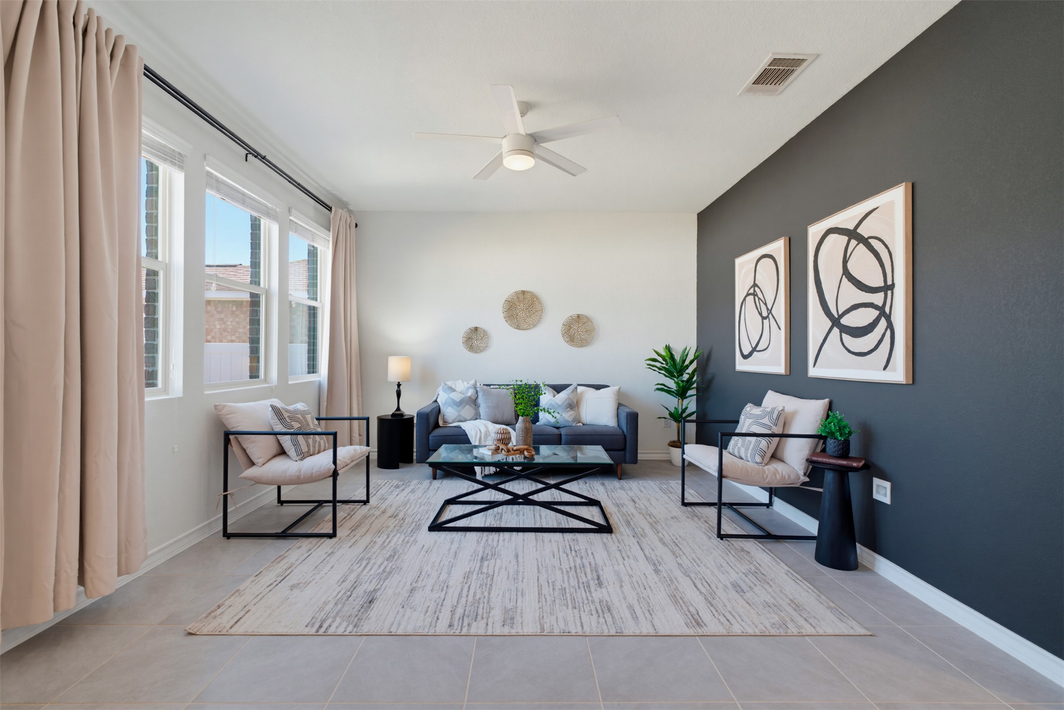 Sunlight streams through large windows onto neutral tiled flooring in this modern living space.