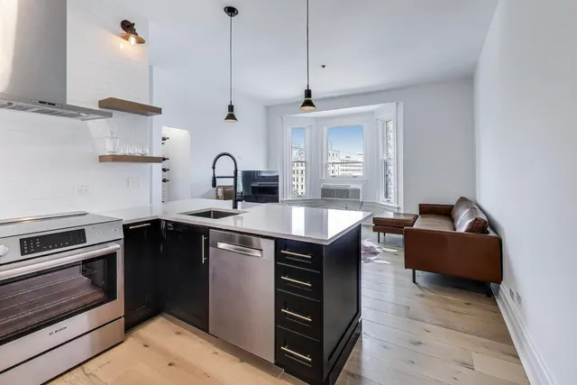 a kitchen with stainless steel appliances granite countertop a sink a stove and a wooden floors