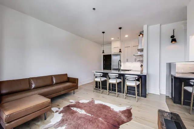 a living room with furniture wooden floor and a kitchen view