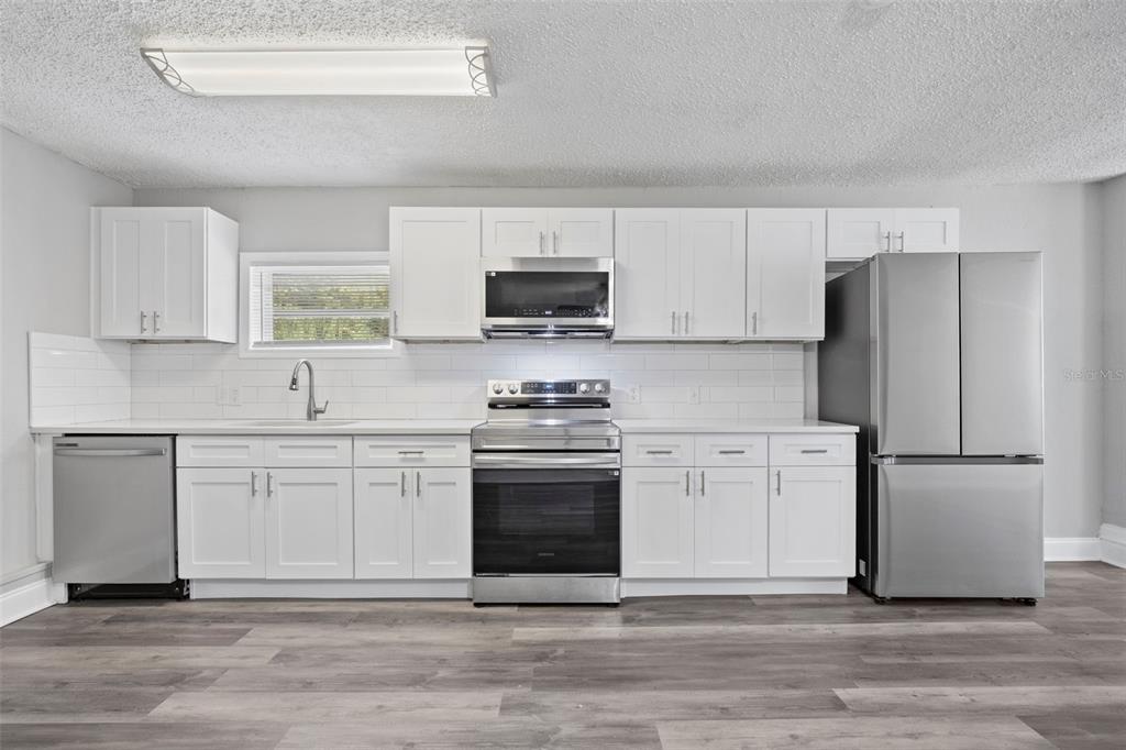 5045 Green Key Road New Port Richey, FL 34652 - Photo 15 of 32 a kitchen with stainless steel appliances white cabinets and a stove top oven