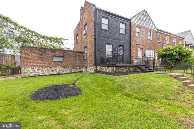 a view of a brick house with a yard and plants