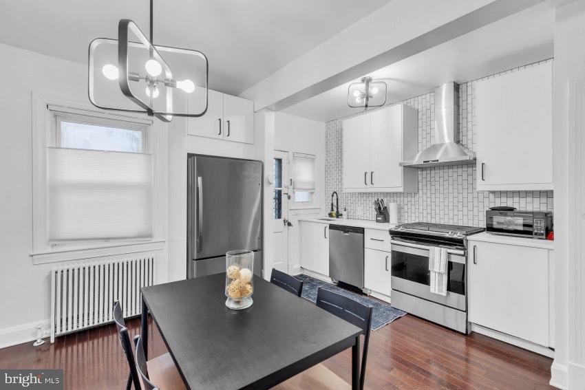 3310 Elbert Street Baltimore, MD 21229 - Photo 7 of 23 a kitchen with stainless steel appliances granite countertop a stove top oven a refrigerator and cabinets with wooden floor