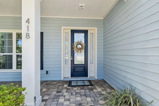 a view of a hallway with wooden door and potted plants in front of door
