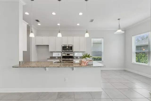 a open kitchen with kitchen island granite countertop stainless steel appliances stove a sink and a microwave