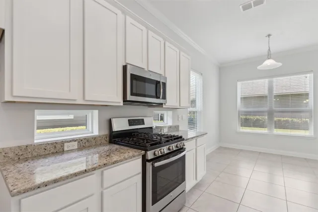a kitchen with granite countertop a sink and white cabinets
