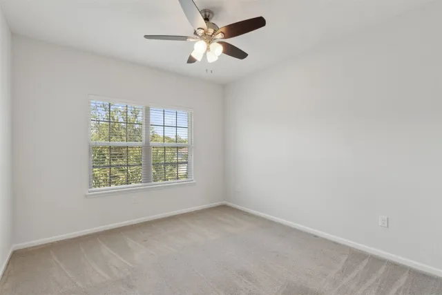 a view of a white house next to a yard with potted plants