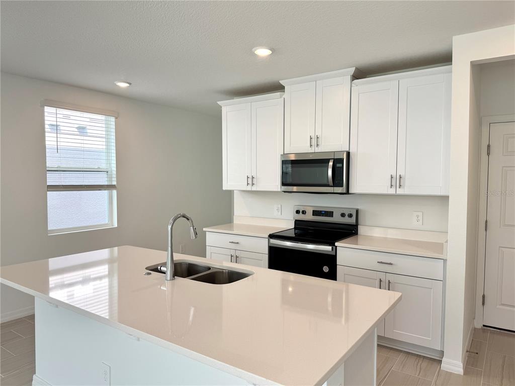 4348 Ranch House Road St. Cloud, FL 34772 - Photo 11 of 58 a kitchen with stainless steel appliances a stove sink microwave and cabinets