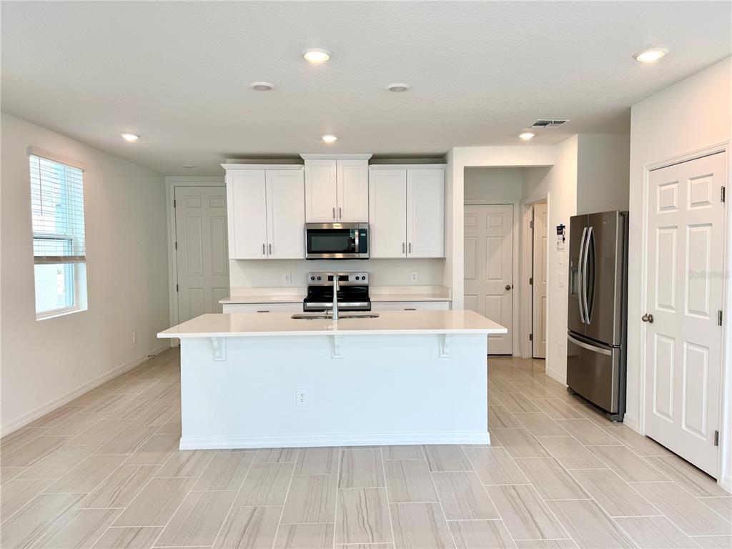 4348 Ranch House Road St. Cloud, FL 34772 - Photo 12 of 58 a kitchen with stainless steel appliances granite countertop a stove top oven a refrigerator a sink and a refrigerator