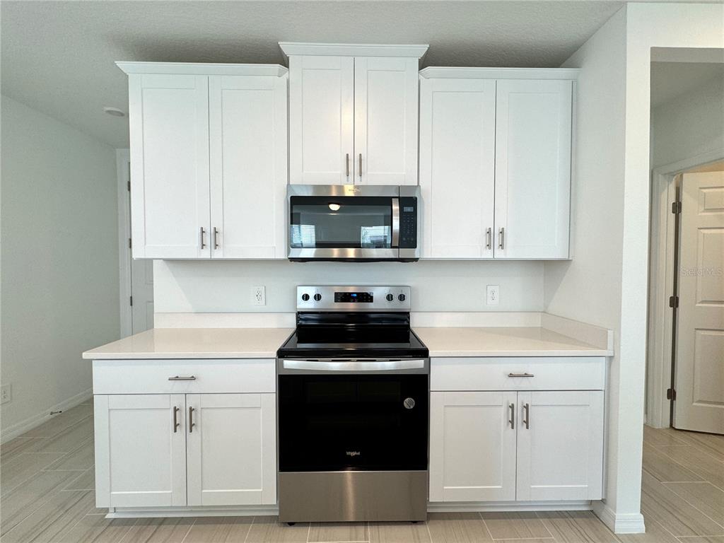 4348 Ranch House Road St. Cloud, FL 34772 - Photo 14 of 58 a kitchen with white cabinets and black appliances