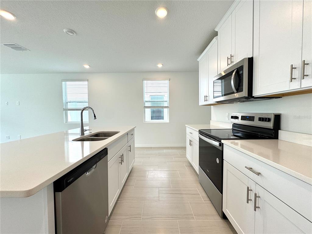 4348 Ranch House Road St. Cloud, FL 34772 - Photo 16 of 58 a large kitchen with stainless steel appliances granite countertop a sink and dishwasher a stove top oven with wooden floor