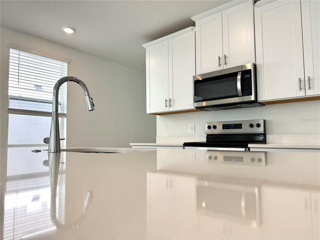 4348 Ranch House Road St. Cloud, FL 34772 - Photo 18 of 58 a kitchen with stainless steel appliances granite countertop white cabinets a microwave a sink and a refrigerator