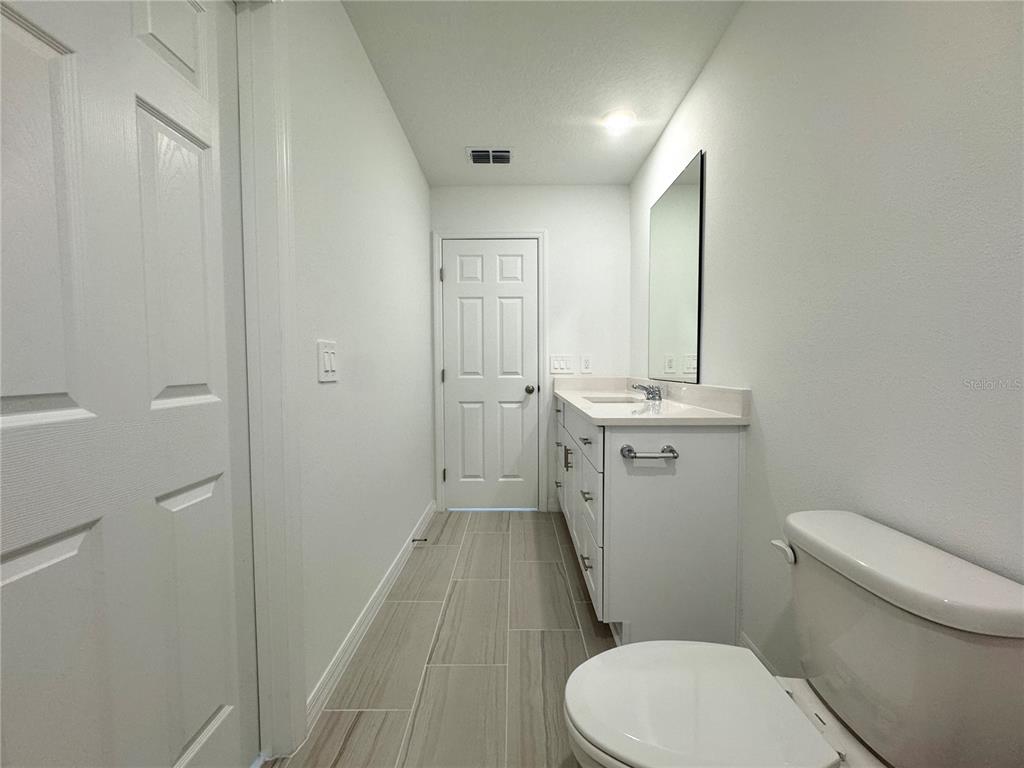 4348 Ranch House Road St. Cloud, FL 34772 - Photo 34 of 58 a bathroom with a sink a toilet a mirror and vanity