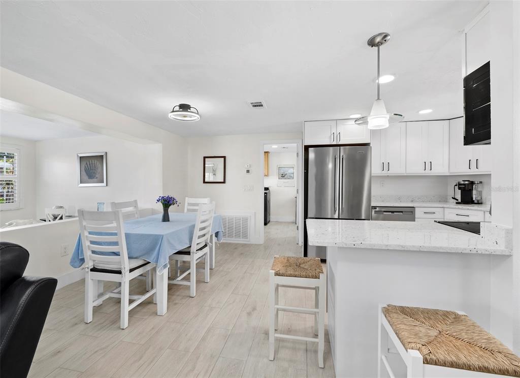 726 Jungle Queen Way Longboat Key, FL 34228 - Photo 8 of 43 a kitchen with stainless steel appliances kitchen island granite countertop a refrigerator a stove a sink a dining table and chairs with wooden floor