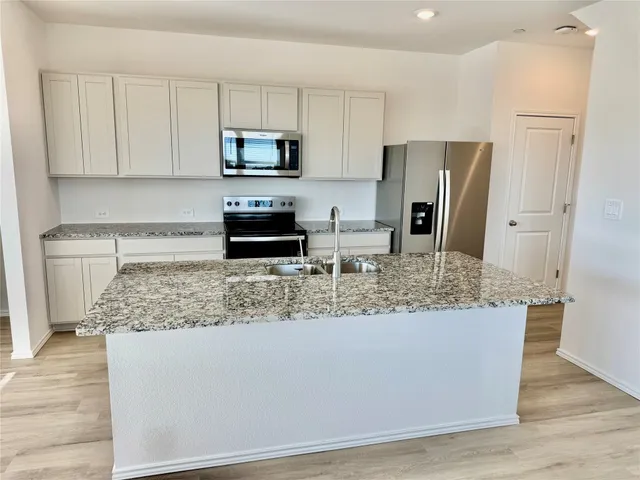 a kitchen with stainless steel appliances granite countertop a refrigerator and a stove top oven