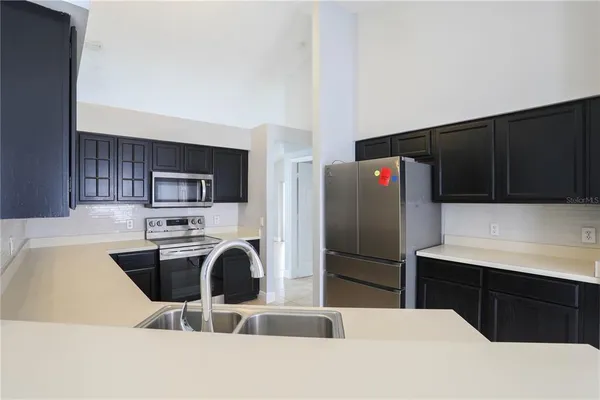 a kitchen with stainless steel appliances kitchen island a refrigerator sink and wooden cabinets
