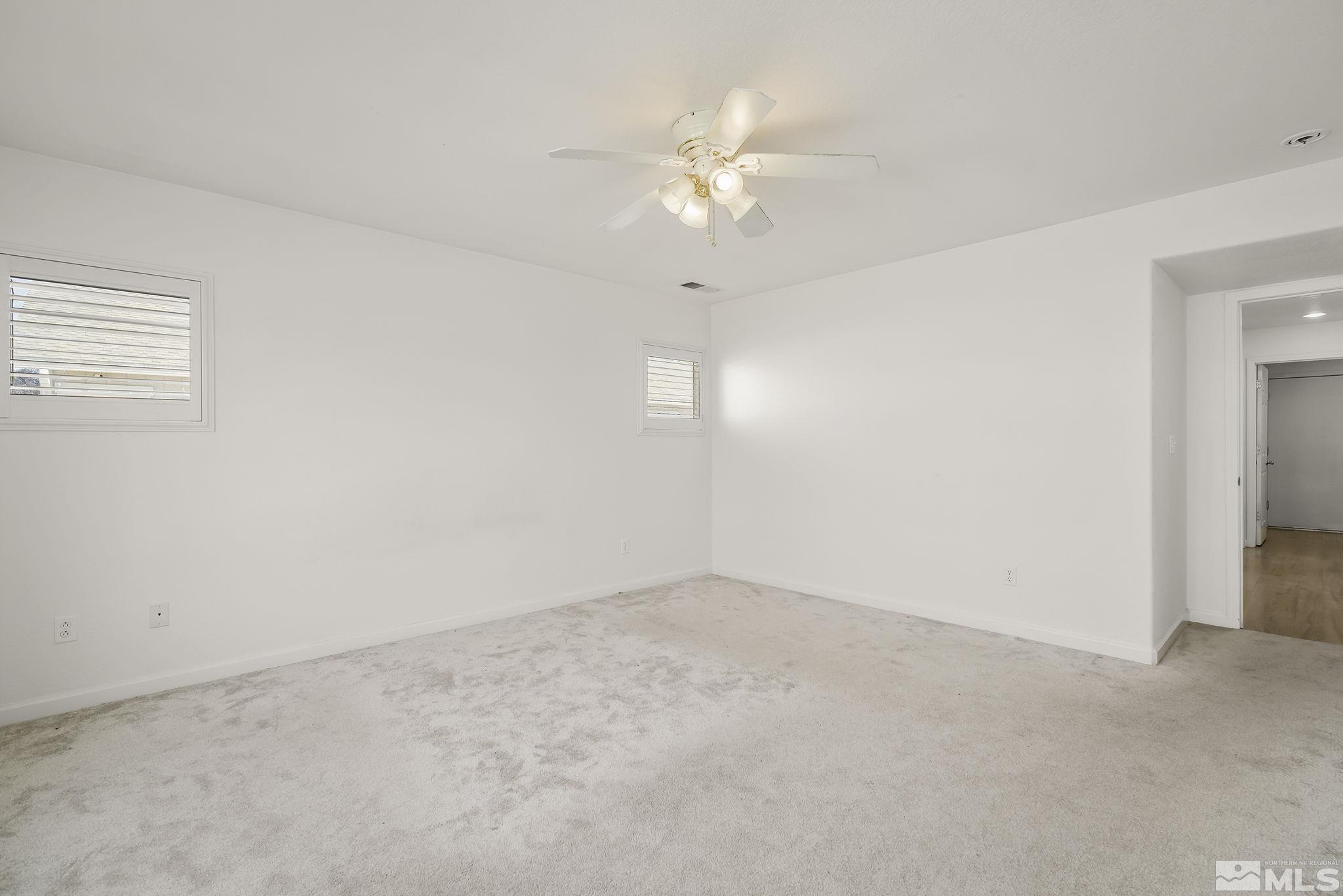 7859 Tulear Street Reno, NV 89506 - Photo 12 of 19 an empty room with a chandelier fan and windows