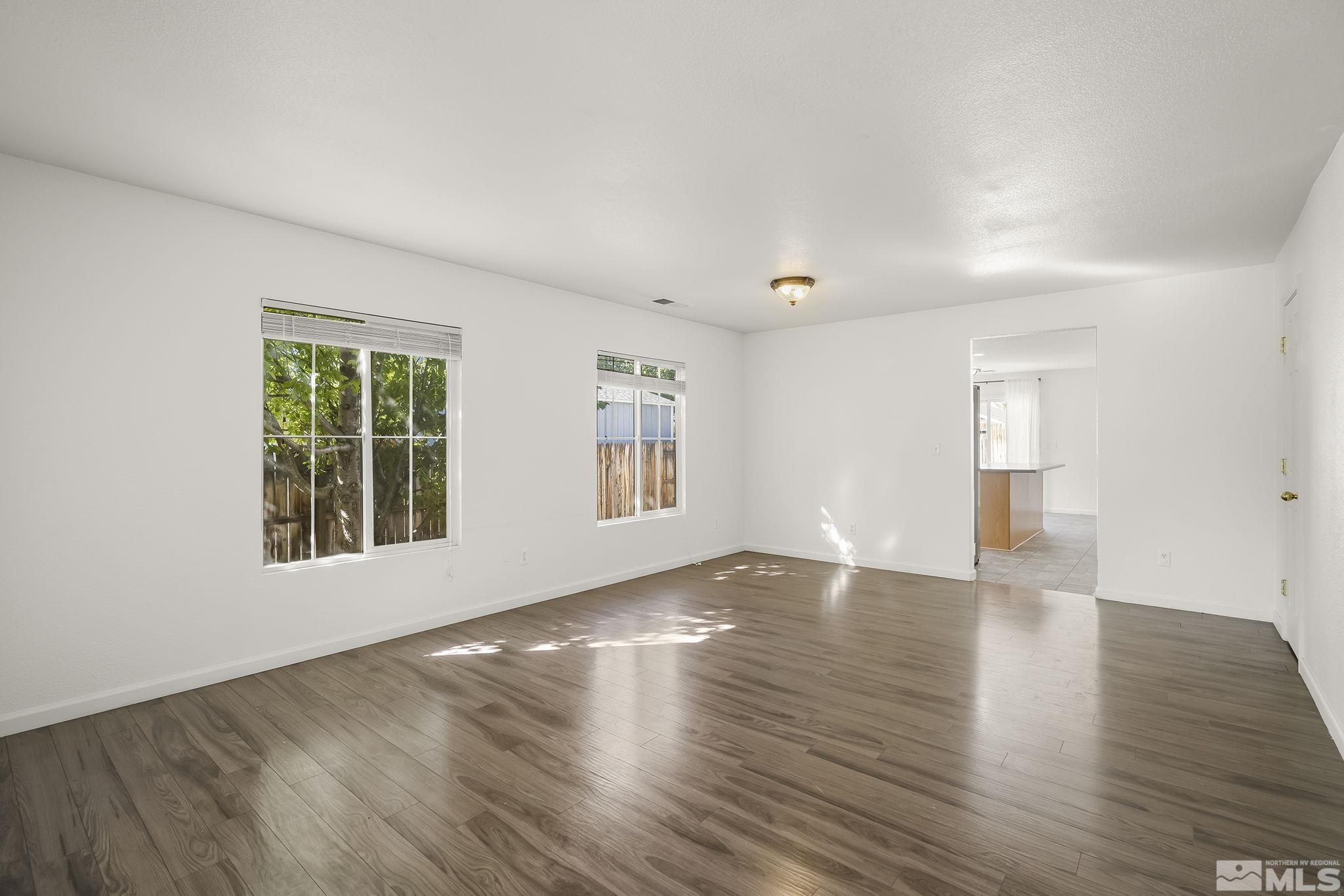 7859 Tulear Street Reno, NV 89506 - Photo 3 of 19 a view of an empty room with wooden floor and windows