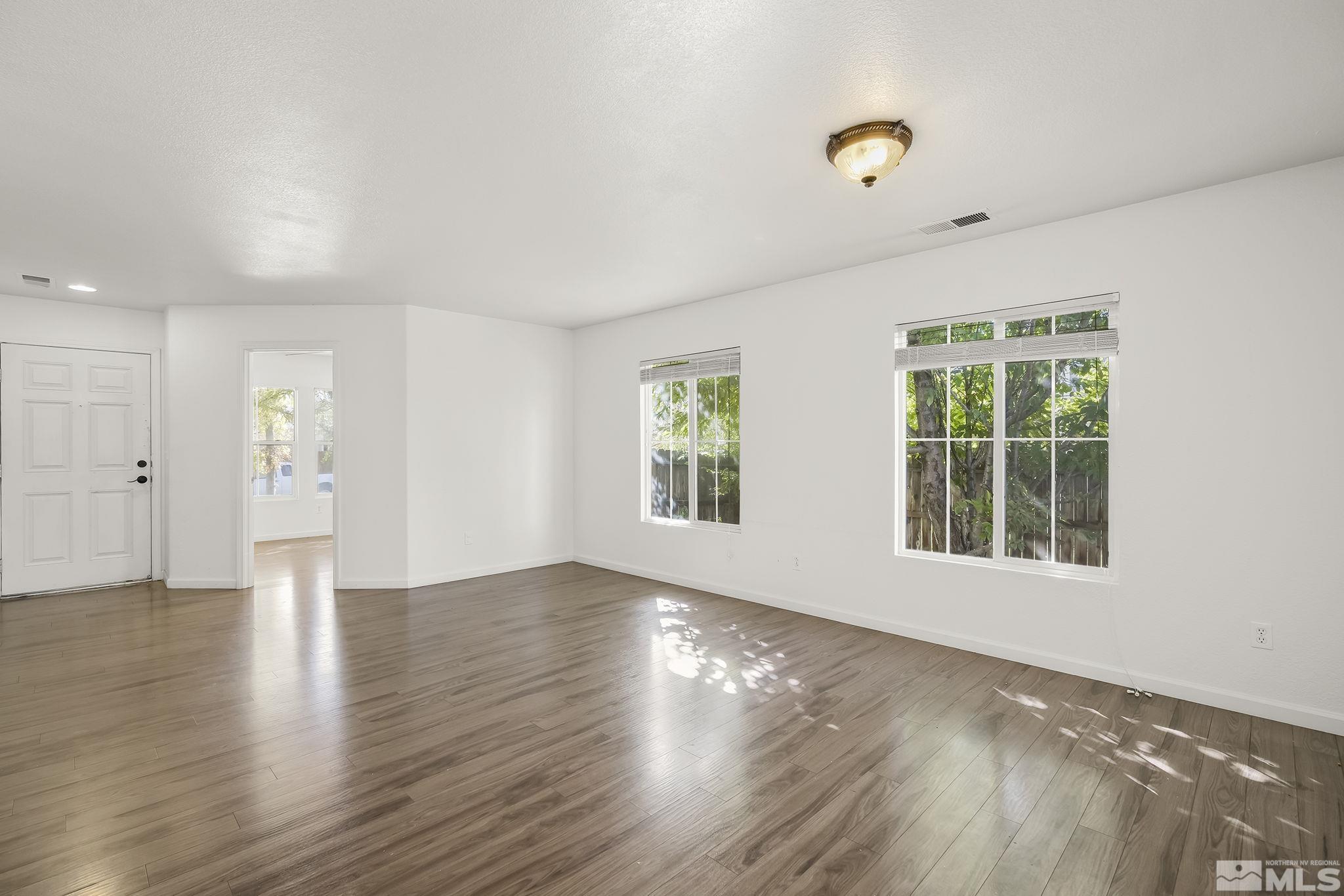 7859 Tulear Street Reno, NV 89506 - Photo 4 of 19 an empty room with wooden floor and windows